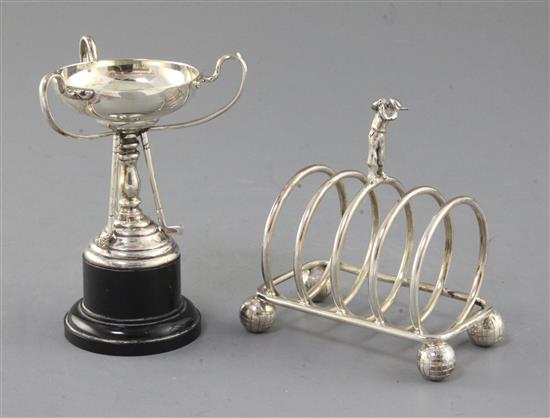 A 1940s golf interest silver toastrack surmounted by a golfer on golf ball feet by W.T. Wiseman, Birmingham toastrack 10cm.